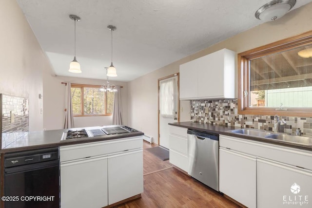 kitchen with wood finished floors, a sink, stainless steel appliances, white cabinets, and backsplash