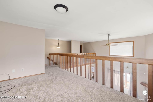 hallway with an upstairs landing, baseboards, and carpet floors