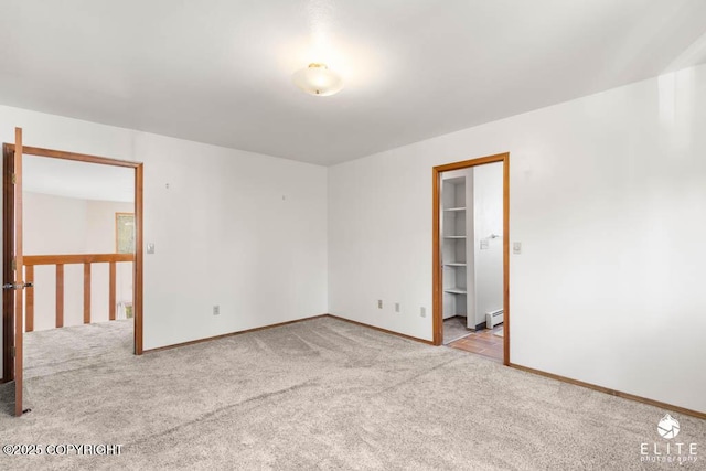 carpeted empty room with baseboards and a baseboard heating unit