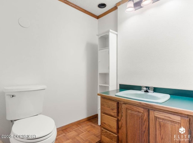 half bath with toilet, ornamental molding, vanity, and baseboards