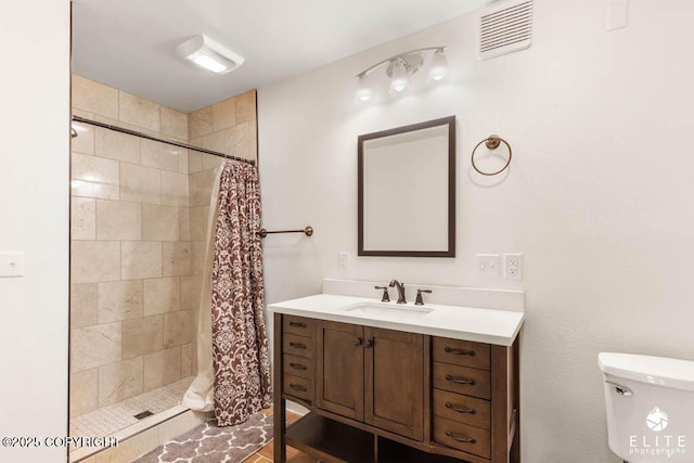 full bathroom with vanity, visible vents, toilet, and a tile shower