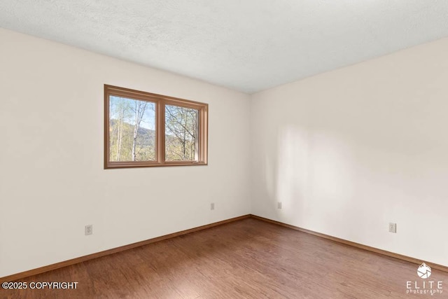 unfurnished room with baseboards, a textured ceiling, and wood finished floors
