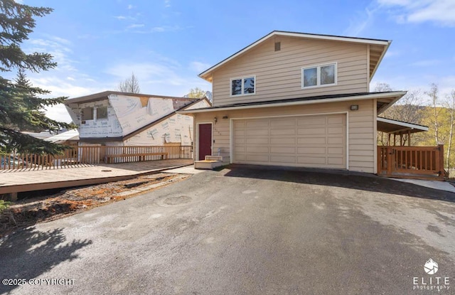 view of front facade with fence, an attached garage, and driveway