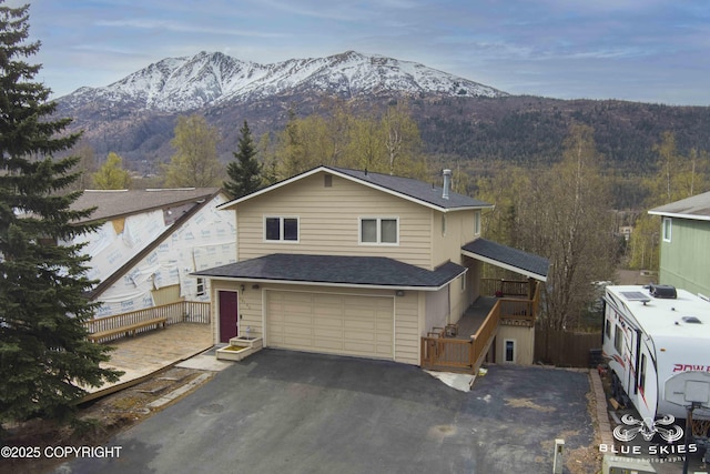 view of front of property with a mountain view, roof with shingles, driveway, and a garage