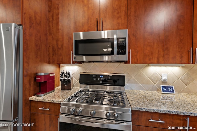 3520 Glenn-Don Cir, Anchorage, AK 99504 - kitchen with stainless steel appliances, tasteful backsplash, light stone counters, and brown cabinetry