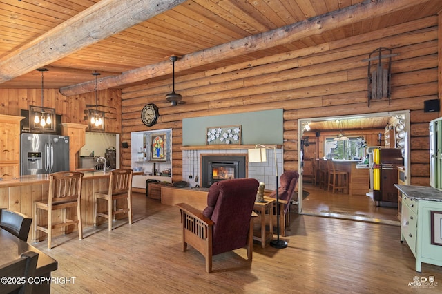 265 Ames Rd, Kenai, AK 99611 - living room featuring beam ceiling, wood ceiling, log walls, wood finished floors, and a tiled fireplace
