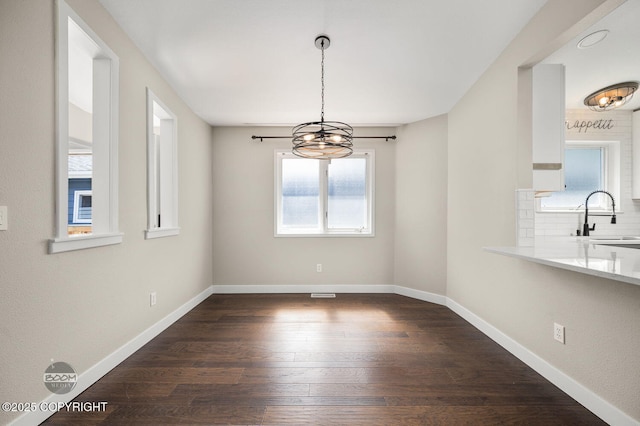 2563 La Honda Dr, Anchorage, AK 99517 - unfurnished dining area featuring a chandelier, a sink, dark wood-type flooring, and baseboards