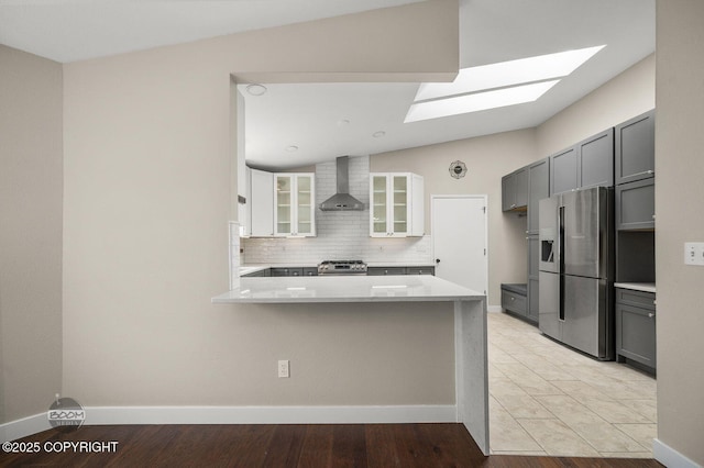 2563 La Honda Dr, Anchorage, AK 99517 - kitchen featuring appliances with stainless steel finishes, wall chimney exhaust hood, a skylight, a peninsula, and tasteful backsplash