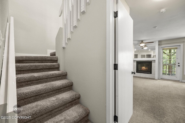 2563 La Honda Dr, Anchorage, AK 99517 - staircase featuring ceiling fan, carpet flooring, and a glass covered fireplace