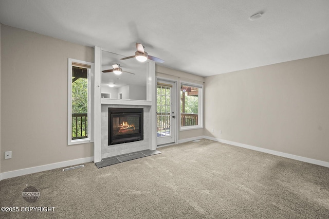 2563 La Honda Dr, Anchorage, AK 99517 - unfurnished living room with a tiled fireplace, ceiling fan, carpet flooring, and baseboards