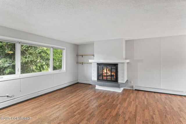 3921 Patricia Ln, Anchorage, AK 99504 - unfurnished living room featuring a textured ceiling, wood finished floors, baseboard heating, a glass covered fireplace, and a baseboard heating unit
