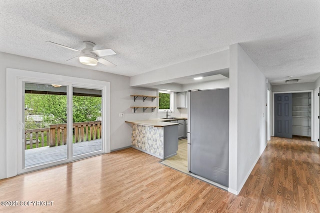 3921 Patricia Ln, Anchorage, AK 99504 - kitchen with a peninsula, a sink, a textured ceiling, light wood-type flooring, and ceiling fan