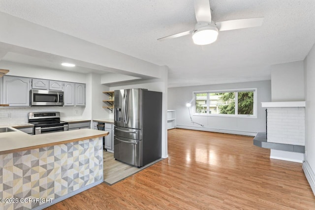 3921 Patricia Ln, Anchorage, AK 99504 - kitchen featuring stainless steel appliances, gray cabinets, a baseboard radiator, light wood-type flooring, and open floor plan