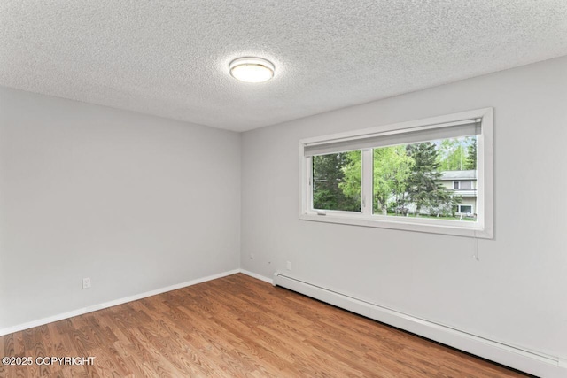 3921 Patricia Ln, Anchorage, AK 99504 - unfurnished room with a baseboard heating unit, wood finished floors, a textured ceiling, and baseboards