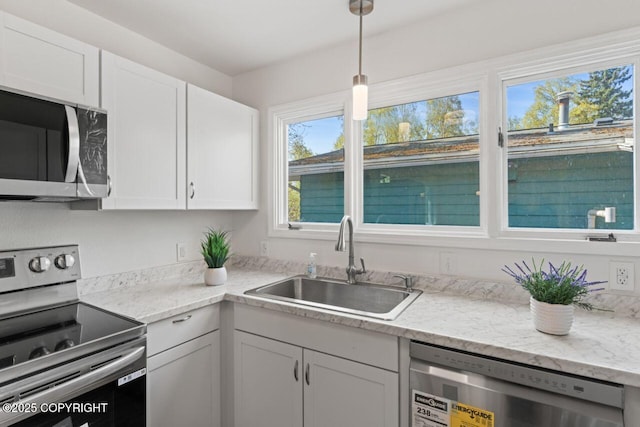 906 Lancaster Dr, Anchorage, AK 99503 - kitchen featuring stainless steel appliances, a sink, white cabinets, decorative light fixtures, and light stone counters