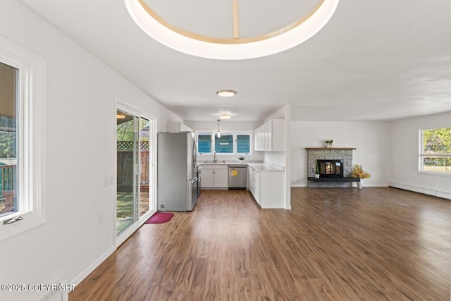 906 Lancaster Dr, Anchorage, AK 99503 - unfurnished living room featuring a baseboard radiator, wood finished floors, a fireplace, a sink, and baseboards