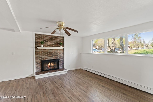 906 Lancaster Dr, Anchorage, AK 99503 - unfurnished living room with a baseboard heating unit, ceiling fan, wood finished floors, a fireplace, and baseboards