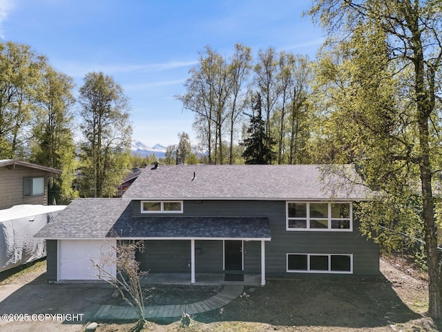 906 Lancaster Dr, Anchorage, AK 99503 - view of front of property featuring roof with shingles, driveway, an attached garage, a patio area, and a mountain view