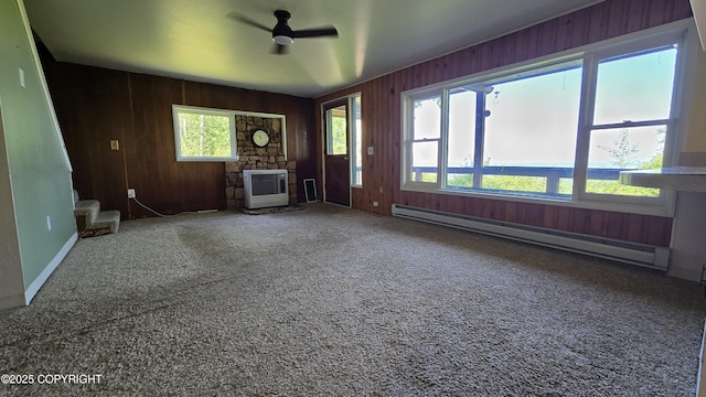 22032 Spring Creek Ln, Chugiak, AK 99567 - unfurnished living room with a baseboard heating unit, wood walls, ceiling fan, carpet floors, and heating unit