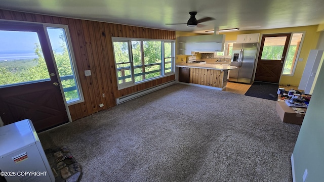 22032 Spring Creek Ln, Chugiak, AK 99567 - kitchen with stainless steel refrigerator with ice dispenser, a baseboard radiator, white cabinetry, plenty of natural light, and wood walls