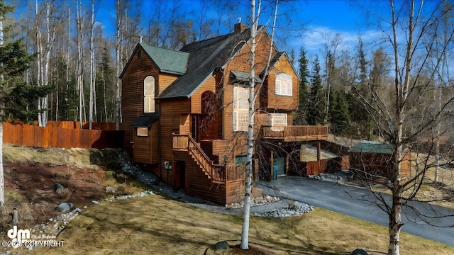 exterior space with a chimney, roof with shingles, and fence