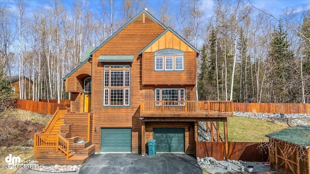chalet / cabin with stairs, aphalt driveway, an attached garage, and fence