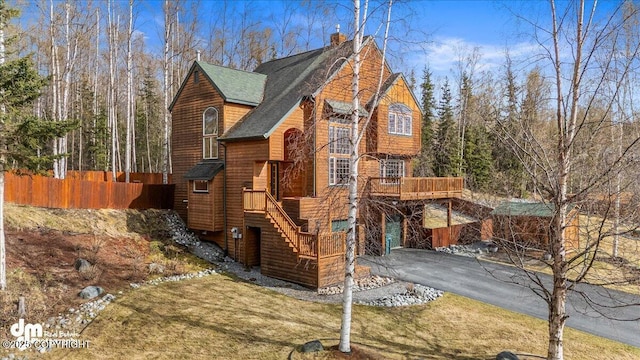 view of side of property featuring a chimney, fence, a deck, stairway, and roof with shingles