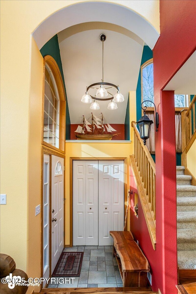 foyer entrance featuring a high ceiling, stairway, arched walkways, and stone tile flooring