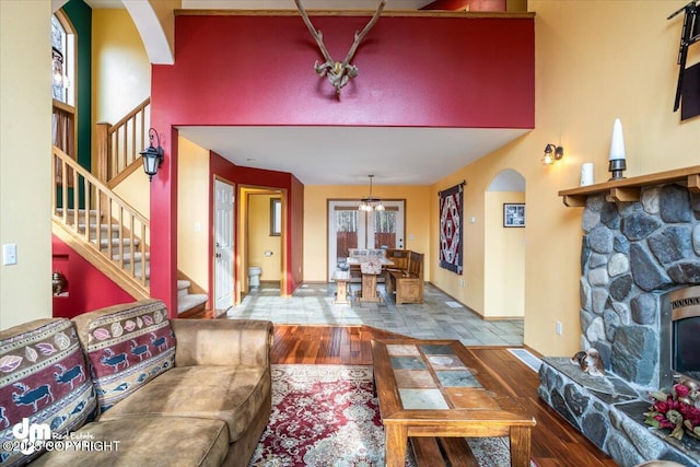 living area featuring stairs, a towering ceiling, wood finished floors, arched walkways, and a fireplace