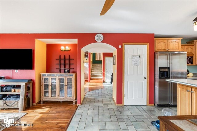 kitchen with ceiling fan, light countertops, arched walkways, and stainless steel refrigerator with ice dispenser
