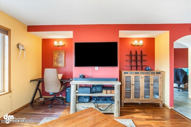 interior space featuring wood finished floors, baseboards, and arched walkways
