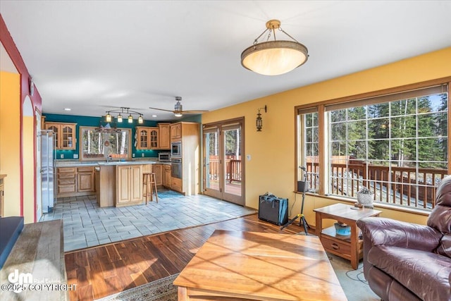 kitchen featuring light wood-style flooring, glass insert cabinets, open floor plan, a kitchen island, and appliances with stainless steel finishes