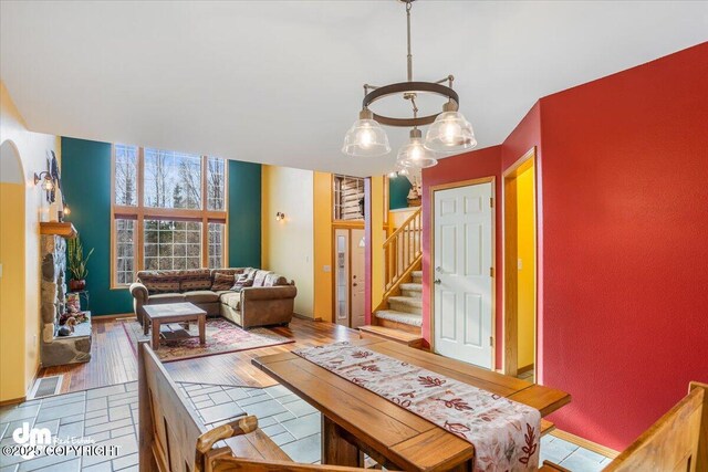 dining room with an inviting chandelier, wood finished floors, arched walkways, and stairs
