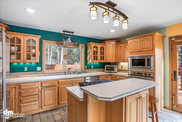 kitchen with a sink, stainless steel appliances, a kitchen island, and plenty of natural light