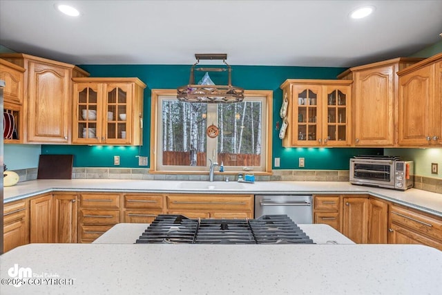 kitchen featuring a sink, a toaster, light countertops, glass insert cabinets, and appliances with stainless steel finishes