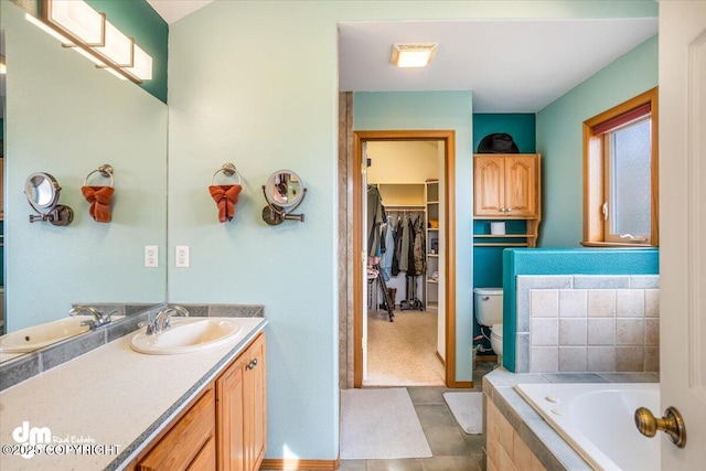 bathroom with toilet, a bath, tile patterned floors, vanity, and a walk in closet
