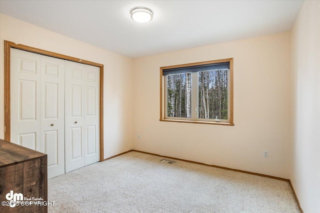 unfurnished bedroom featuring baseboards, a closet, visible vents, and carpet floors