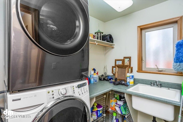 washroom featuring stacked washing maching and dryer, laundry area, and a sink