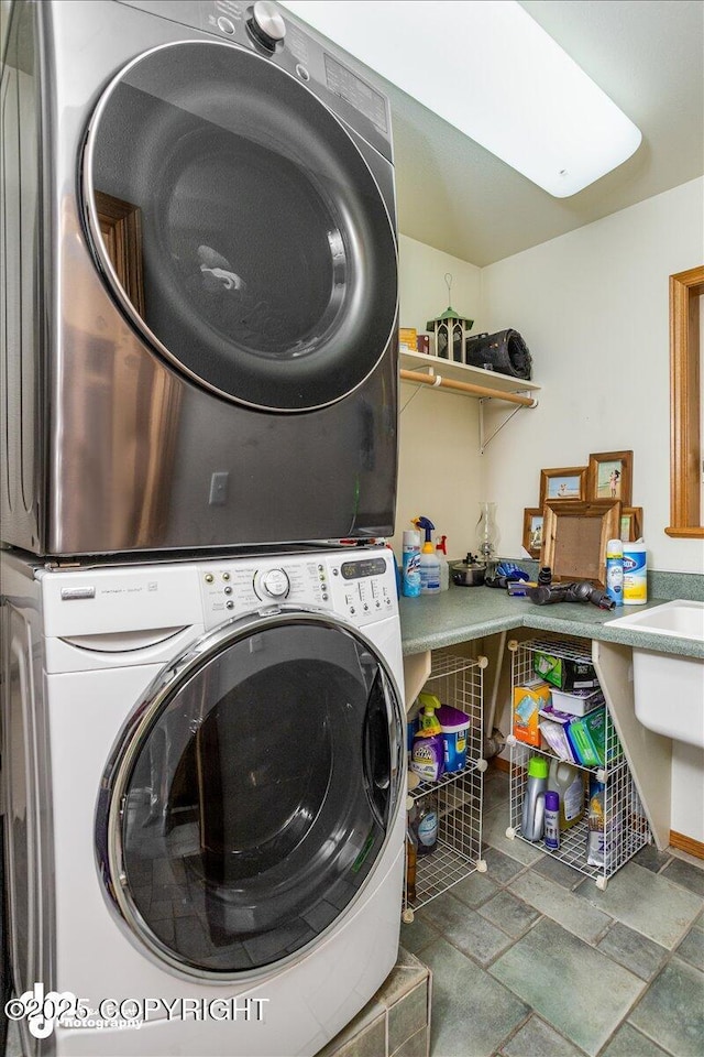 clothes washing area with stacked washing maching and dryer and laundry area