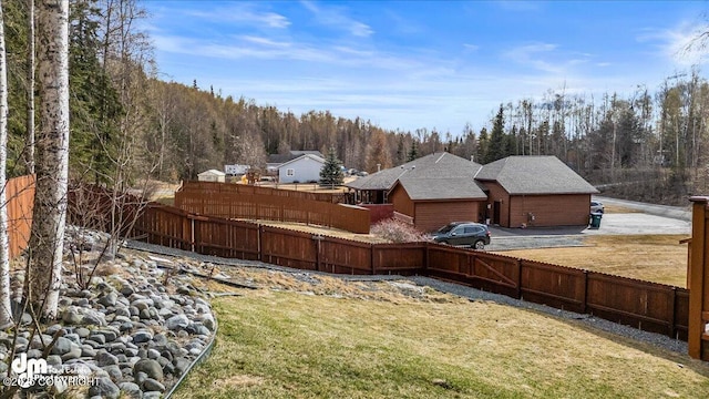 view of yard with a fenced backyard and a view of trees