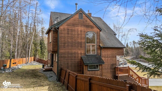 back of property featuring roof with shingles, a chimney, a lawn, and a fenced backyard