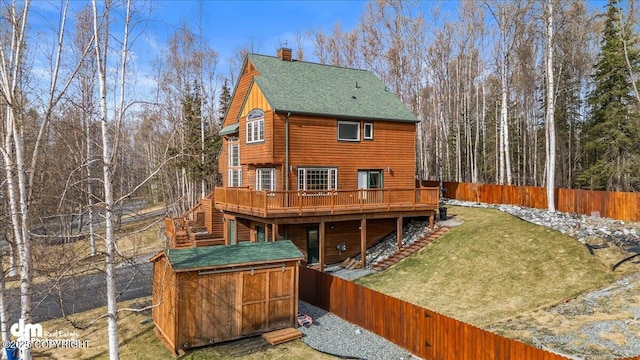rear view of property with a chimney, stairs, a deck, roof with shingles, and a storage shed