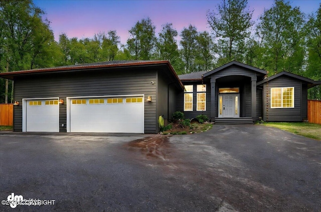 view of front of house featuring driveway, a garage, and fence
