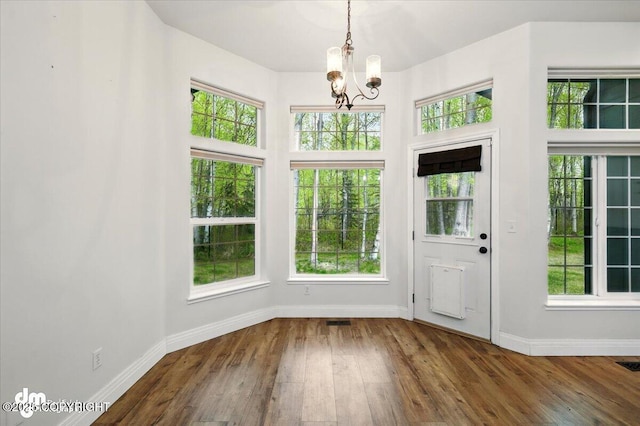 entryway with a chandelier, baseboards, wood-type flooring, and healthy amount of natural light