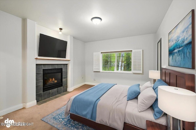 carpeted bedroom with a tiled fireplace and baseboards