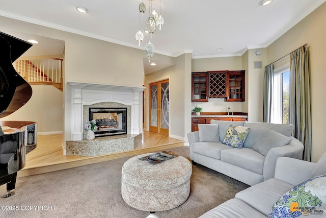 carpeted living area with recessed lighting, crown molding, baseboards, a premium fireplace, and wood finished floors