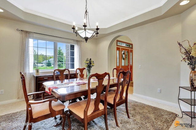 dining area featuring arched walkways, a raised ceiling, crown molding, recessed lighting, and a chandelier