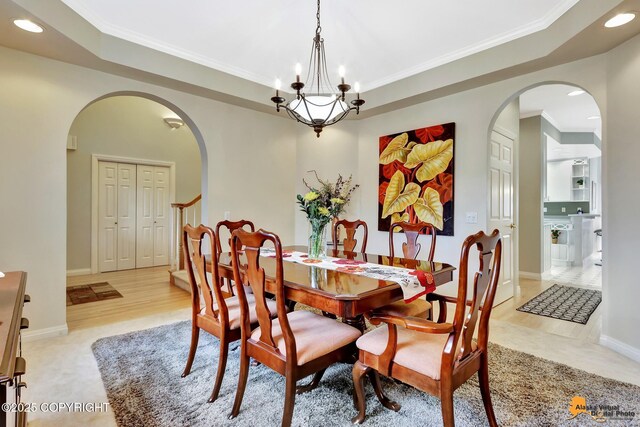 dining area featuring arched walkways, recessed lighting, a raised ceiling, ornamental molding, and a chandelier