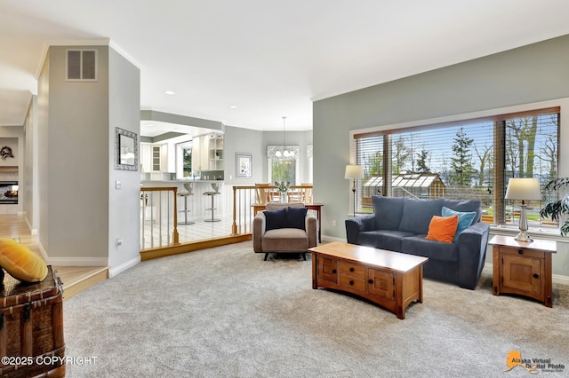 living area featuring light colored carpet, a chandelier, baseboards, and ornamental molding