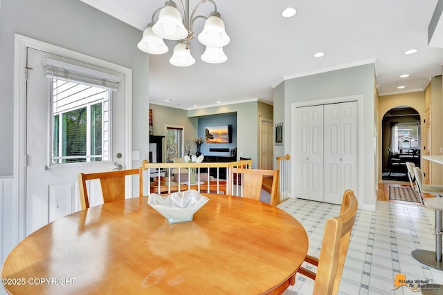 dining space with arched walkways, ornamental molding, a chandelier, recessed lighting, and light flooring